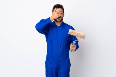 Ressam, beyaz arka planda izole edilmiş bir boya silindiri tutuyor. Gözleri elle kapatıyor.