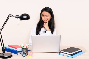 İş yerinde bej arka planda izole edilmiş dizüstü bilgisayarı olan Asyalı bir kız.