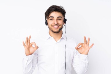 Tele pazarlamacı Arap bir adam beyaz arka planda izole edilmiş bir kulaklıkla çalışıyor.