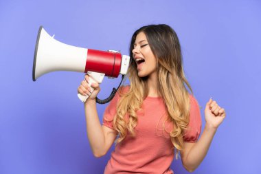 Mavi arka planda izole edilmiş genç bir Rus kız megafonla bir şey duyurmak için bağırıyor.