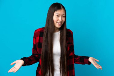 Genç Çinli kız soyutlanmış mavi arka planda mutlu ve gülümsüyor