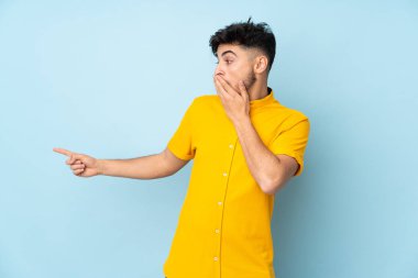 Bir yandan işaret ederken diğer yandan sürpriz bir ifadeyle yalıtılmış arap yakışıklı adam.