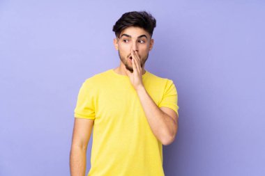 Soyutlanmış arka planda yaşayan yakışıklı Arap bir adam. Yan tarafa bakarken sürpriz bir jest yapıyor.