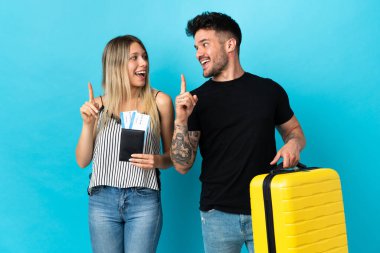 Kafkasyalı genç çift mavi arka planda izole bir şekilde seyahat edecek. Çözümün farkına varmak için parmağını kaldıracak.