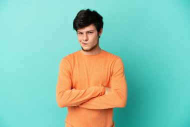 Genç Rus adam mutsuz bir ifadeyle mavi arka planda izole edildi.