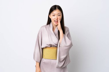 Kimono giyen genç bir Çinli kız izole edilmiş arka planda ağzı açık bağırıyor.
