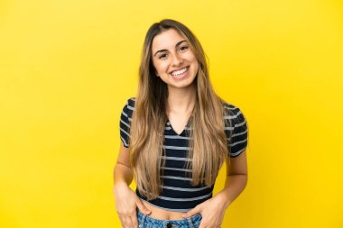 Sarı arka planda izole edilmiş genç beyaz kadın gülüyor.