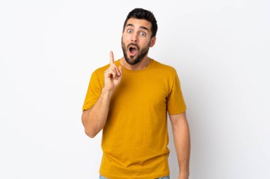 Beyaz arka planda sakallı yakışıklı genç adam çözümü bulmak için parmağını kaldırıyor.