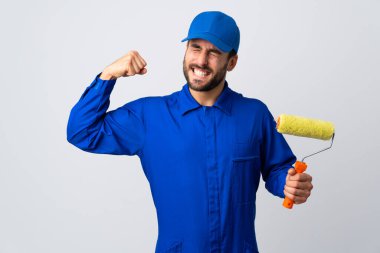 Beyaz arka planda izole edilmiş bir boya silindiri tutan ressam güçlü bir hareket yapıyor.