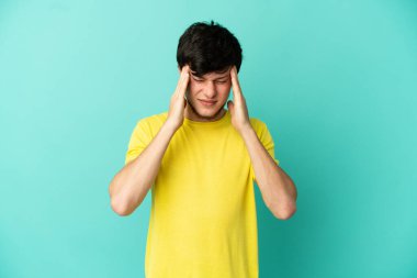 Genç Rus adam mavi arka planda baş ağrısı ile izole edildi.