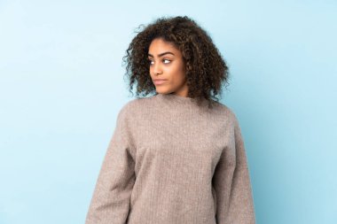 Genç Afrikalı Amerikalı kadın mavi arka planda izole edilmiş.