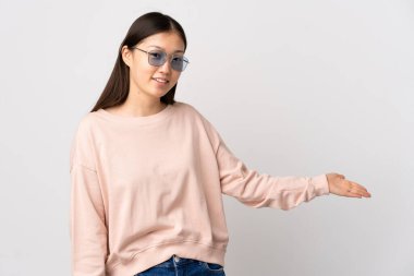 İzole edilmiş beyaz arka planda genç bir Çinli kız davet etmek için ellerini yana uzatıyor.