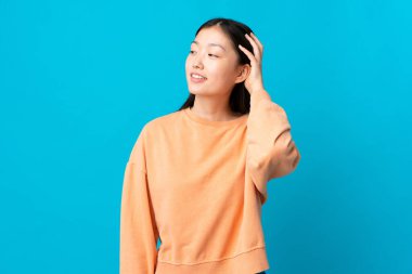 Soyutlanmış mavi arka planda genç bir Çinli kız bir fikir düşünüyor.