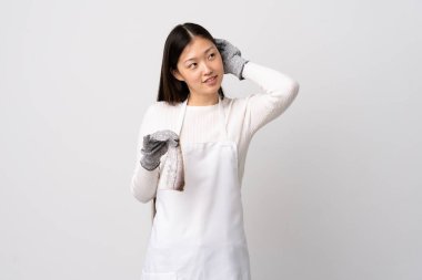 Çinli balıkçı önlük takıyor ve çiğ balığı izole edilmiş beyaz arka planda tutuyor.