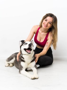 Genç spor kızı köpeğiyle yerde oturuyor.
