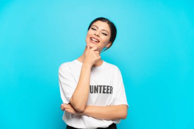 Genç Rus gönüllü kız mavi arka planda mutlu ve gülümsüyor.