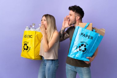 Kafkasyalı genç çift, mor arka planda izole edilmiş bir şekilde ağızları sonuna kadar açık bağırıyor.