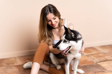 Genç ve güzel bir kadın. İri köpeğiyle içeride yerde oturuyor.