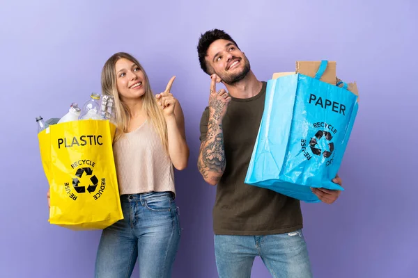 Reciclagem Jovem Casal Caucasiano Isolado Fundo Roxo Apontando Com Dedo — Fotografia de Stock