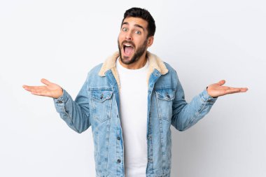 Beyaz arka planda sakallı yakışıklı genç adam şok olmuş yüz ifadesi var.