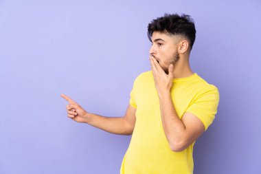 Bir yandan işaret ederken diğer yandan sürpriz bir ifadeyle yalıtılmış arap yakışıklı adam.