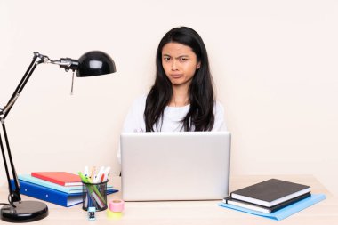 İş yerinde bej arka planda izole edilmiş dizüstü bilgisayarı olan Asyalı kız üzgün.