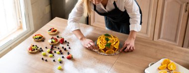 Genç pasta şefi dilimlenmiş portakallı kek pişiriyor.