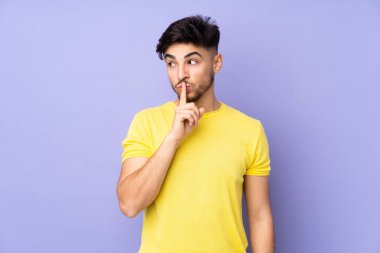 Münzevi bir geçmişi olan Arap yakışıklı bir adam sessizlik işareti gösteriyor. Parmağını ağzına sokuyor.