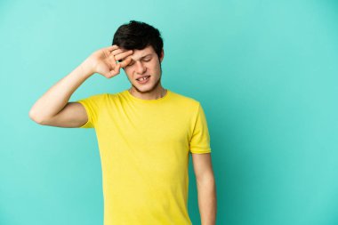 Genç Rus adam mavi arka planda izole edilmiş, yorgun ve hasta bir ifadeyle.