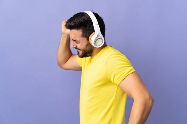 Mor arka planda sakallı genç yakışıklı adam müzik ve dans dinliyor.