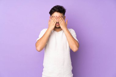 İzole edilmiş arka planda, gözleri elleriyle kaplayan Arap yakışıklı bir adam.