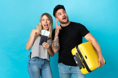 Kafkasyalı genç bir çift mavi arka planda izole bir şekilde seyahat edecek.