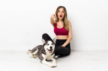 Köpeğiyle yerde oturan genç kız şaşırmış ve ön tarafı işaret ediyor.