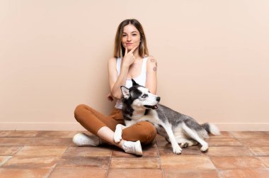 İri köpeğiyle yerde oturan genç ve güzel bir kadın.