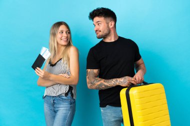 Mavi arka planda tek başına seyahat edecek olan beyaz bir çift gülümseyerek omzunun üzerinden bakıyor.