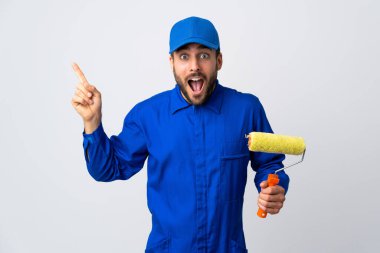 Beyaz arka planda izole edilmiş bir boya silindiri tutan ressam şaşırmış ve parmağıyla kenarı işaret ediyor.