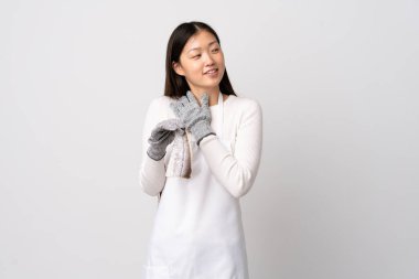 Çinli balıkçı önlük takıyor ve beyaz arka planda çiğ balık tutuyor gülümserken yukarı bakıyor.