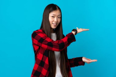 İzole edilmiş mavi arka plan üzerinde genç bir Çinli kız ilan vermek için kopyalama alanı tutuyor.