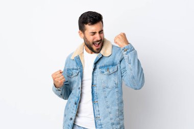 Beyaz arka planda sakallı yakışıklı genç adam zaferi kutluyor.
