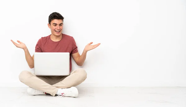 青少年男子坐在花盆上 他的笔记本电脑上 双手拿着版权 — 图库照片