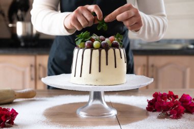 Genç pasta şefi mutfakta meyveli ev yapımı çikolatalı kek pişiriyor.