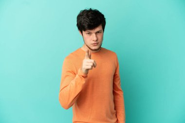 Mavi arka planda izole edilmiş genç bir Rus hayal kırıklığına uğramış ve cepheyi işaret ediyor.