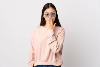 İzole edilmiş beyaz arka planı olan genç bir Çinli kız ağızlarını eliyle kapatıyor.