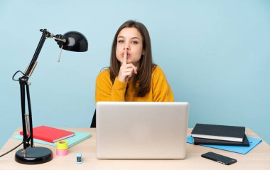 Evinde okuyan öğrenci kız mavi arka planda izole bir şekilde sessizce hareket ediyor. Parmağını ağzına sokuyor.