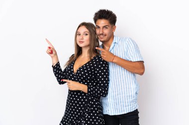 Beyaz arka planda izole edilmiş genç beyaz bir çift parmak göstererek bir ürün sunuyor.