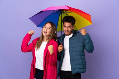 Mavi arka planda şemsiyesi olan çift zaferi kutluyor.