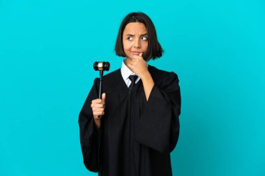 İzole edilmiş mavi arkaplan üzerinde şüpheyle ve kafa karıştırıcı yüz ifadesiyle hakim