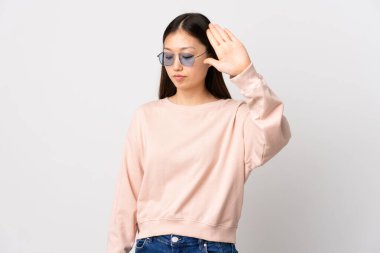 Genç Çinli kız izole edilmiş beyaz arka planda durma hareketi yapıyor ve hayal kırıklığına uğruyor.