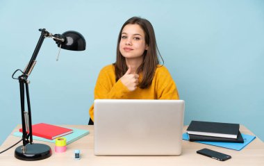 Öğrenci kız, mavi arka planda izole bir şekilde evinde ders çalışıyor.