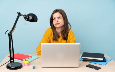 Öğrenci kız, mavi arka planda izole bir şekilde evinde ders çalışıyor.